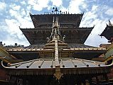 Kathmandu Patan Golden Temple 07 Main Temple With Swayambhu Chaitya In Front The large rectangular Golden Temple in Patan has three roofs and a copper-gilded faade. The long metal strips coming down from the roof are supposed to provide a slide for the gods when they descend to answer prayers. In the foreground is the roof of the Swayambhu Chaitya.